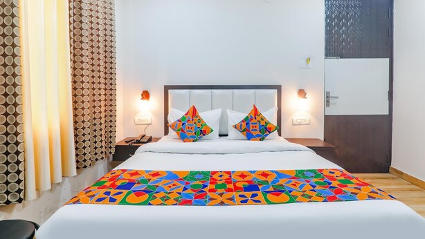 Camera d'albergo con un letto, due comodini, un telefono e una porta con pannello decorativo.