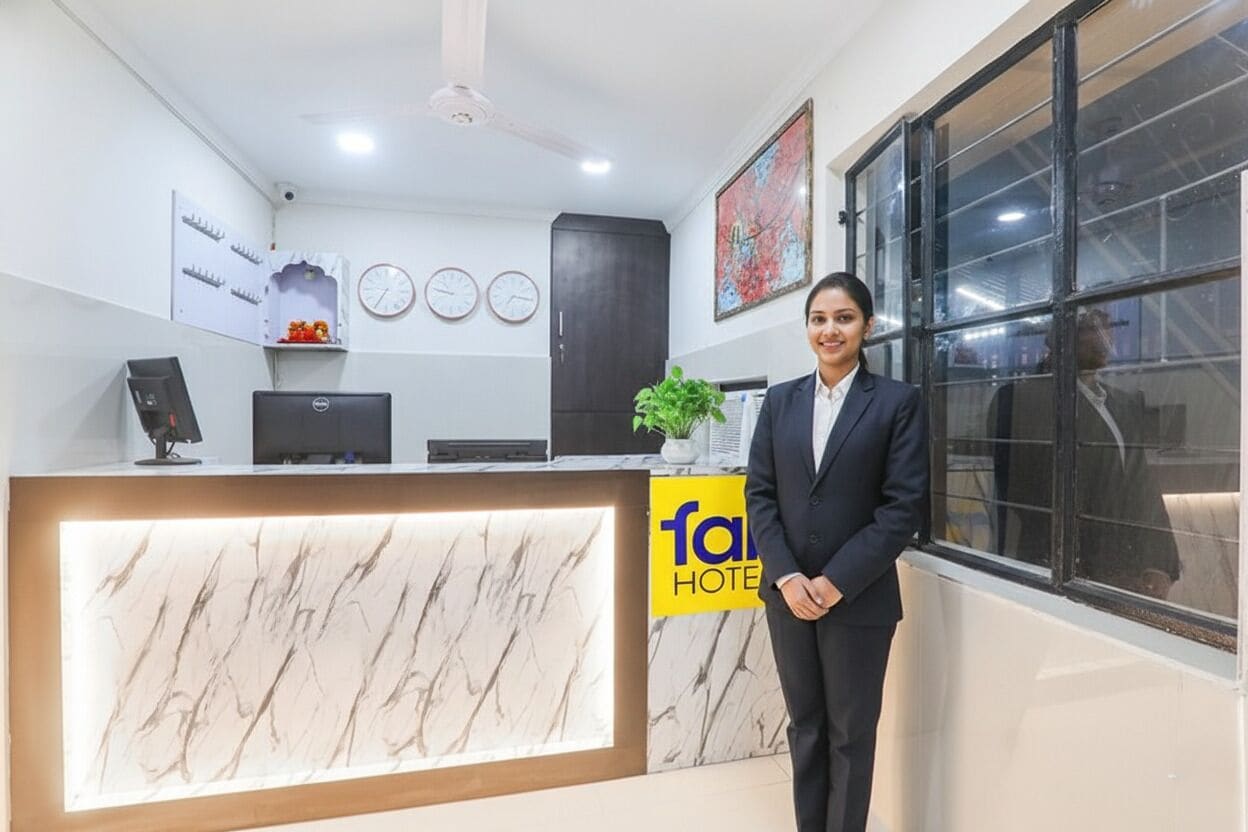 A hotel reception desk with a marble front, clocks, and a large window.