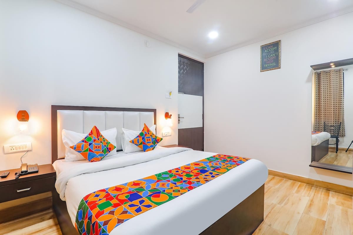 A hotel room with a large bed, two bedside lamps, a bedside telephone, and a mirror on the wall.