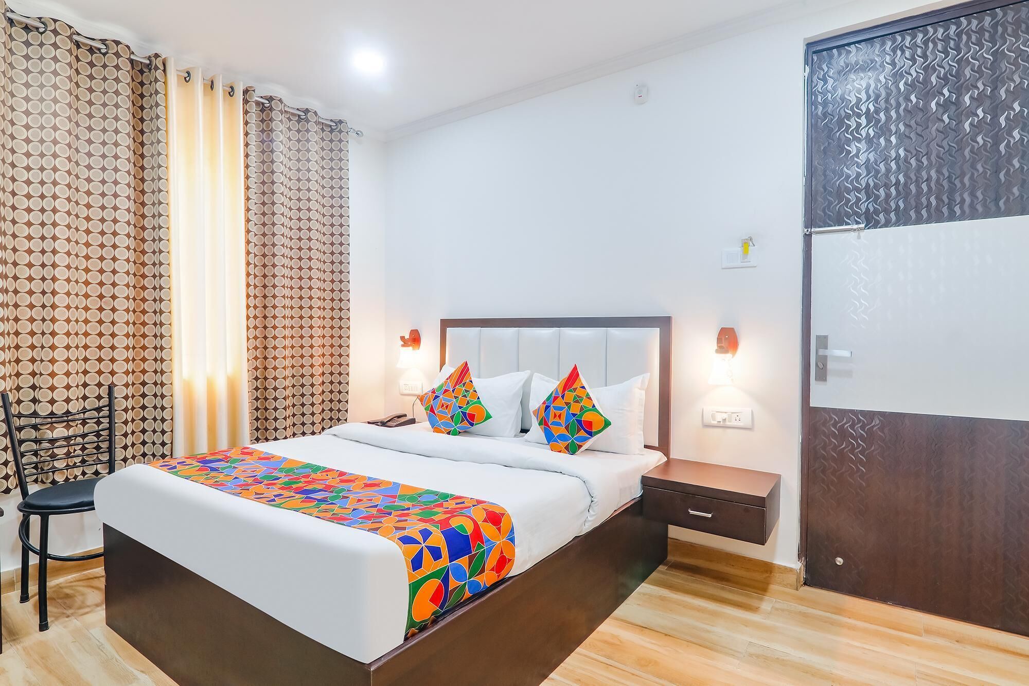 A hotel room with a bed, a chair, a nightstand, and a wardrobe.