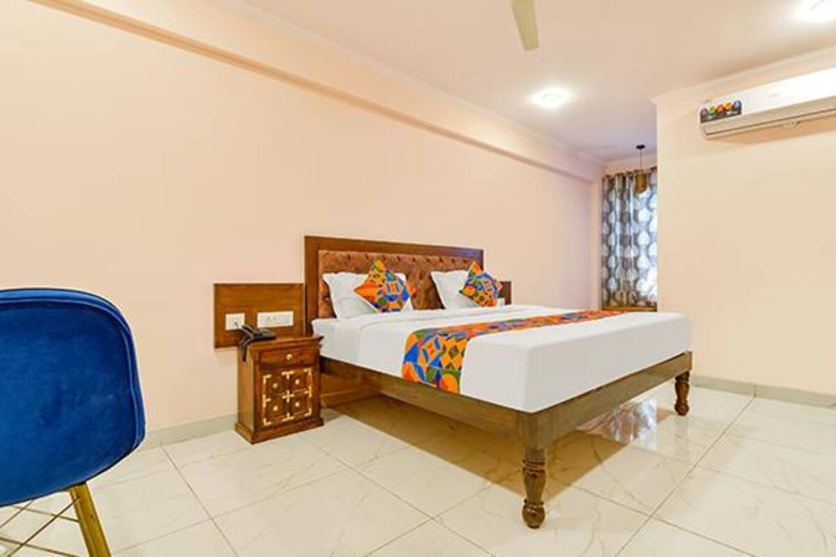 A bedroom with a wooden bed, a nightstand, a blue chair, and a tiled floor.