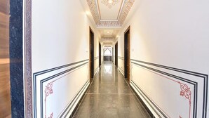 A long, narrow hallway with ornate ceiling decorations and a polished floor. - Fabhotel Shekhawati Heritage (Jaipur)