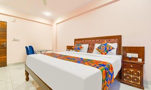 Ein Hotelzimmer mit einem großen Bett, einem Nachttisch, einem Stuhl und einem kleinen Schrank.
