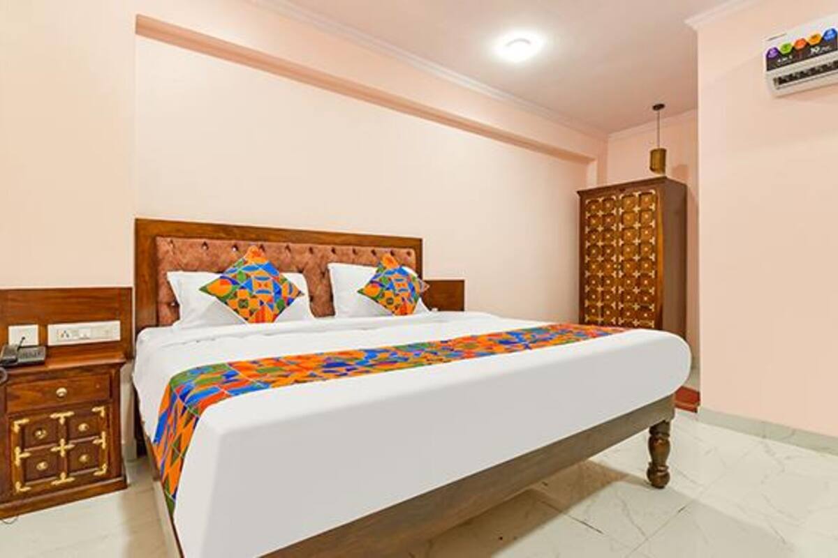 A neatly made bed with a colorful blanket, a wooden headboard, and a bedside table with a lamp.