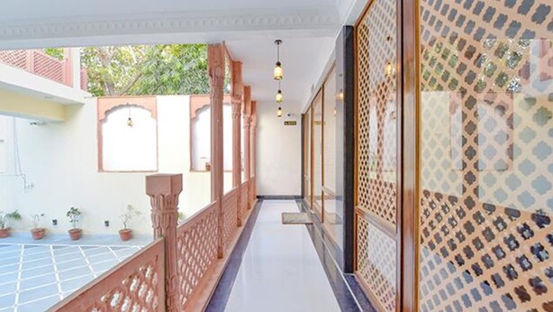 A corridor with a wooden railing, potted plants, and a patterned wall. - Fabhotel Shekhawati Heritage (Jaipur)