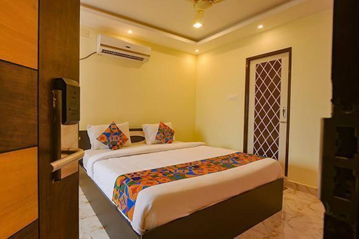 A hotel room with a bed, a wardrobe, an air conditioning unit, and a door with a decorative grille.