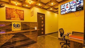 A reception area with a marble reception desk, a Buddha statue, a television screen, and a wooden ceiling. - FabHotel The Fortune Inn - Chromepet (Chennai)