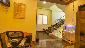 A hotel lobby with a staircase, a reception desk, and a fish tank. - FabHotel The Fortune Inn - Chromepet (Chennai)