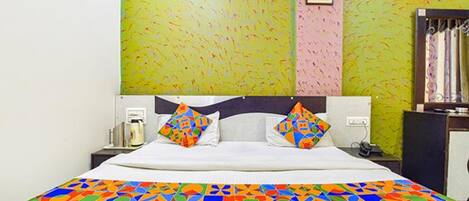 Un letto con una coperta colorata a motivi geometrici, una testiera e un comodino con una lampada.