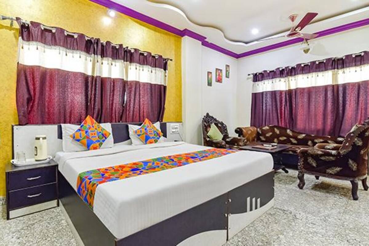 A bedroom with a bed, nightstands, a dresser, a sofa, and curtains.