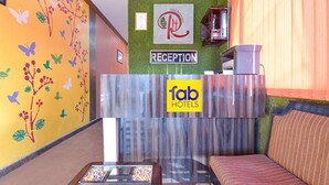 A reception area with a 'Reception' sign, a 'fab hotels' sign, a sofa, and a glass table. - Fabexpress Relax Inn I (Udaipur)
