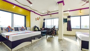 A hotel room with a bed, a chair, a desk, and large windows. - Fabexpress Relax Inn I (Udaipur)