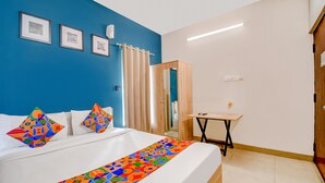 A hotel room with a bed, a small table, and a mirror. - Fabhotel Silverkey (Barasat)