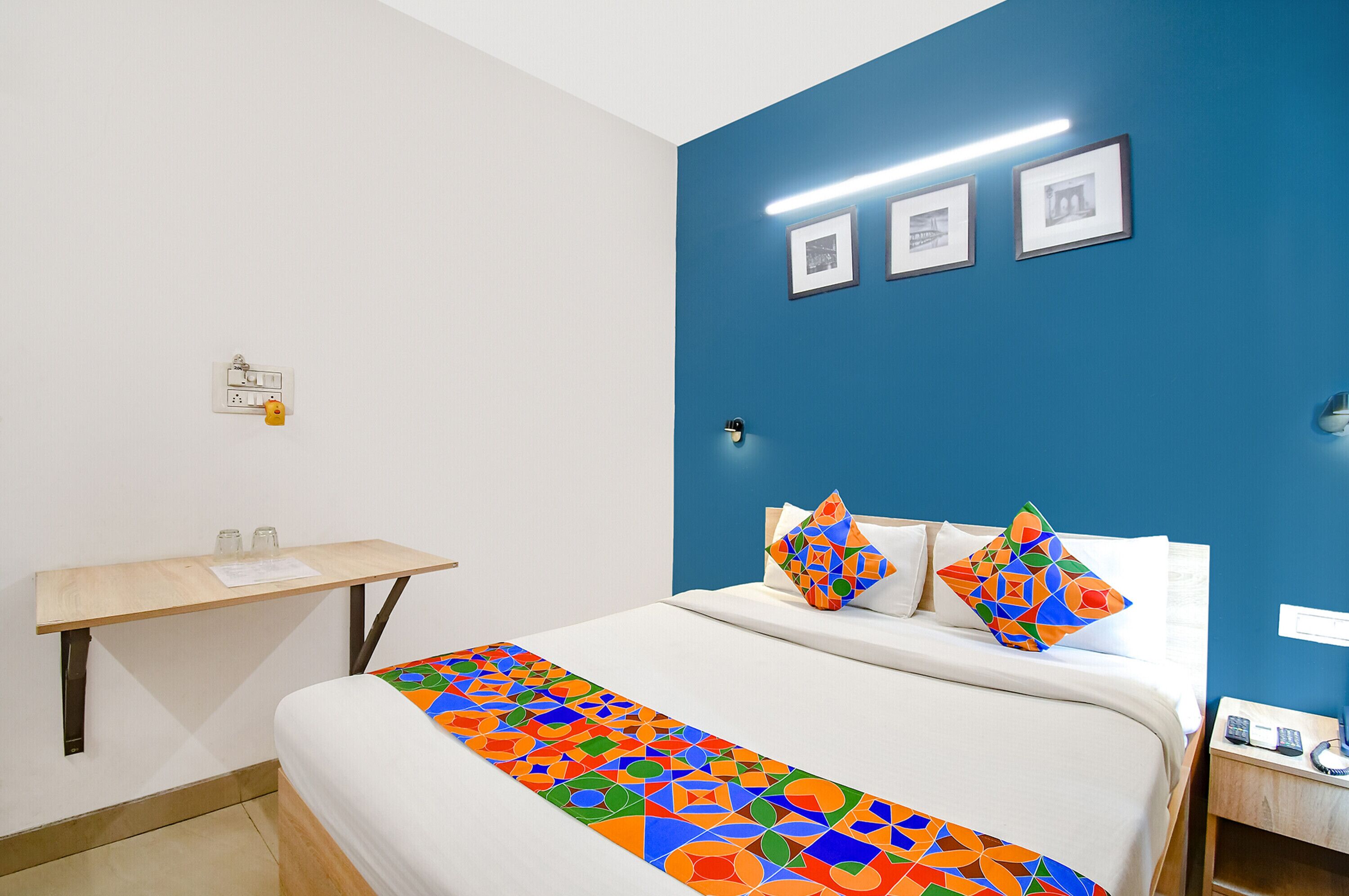 A hotel room with a bed, a desk, and a nightstand.