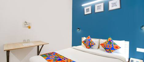 A hotel room with a bed, a desk, and a nightstand.