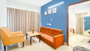 A room with a sofa, armchair, and a small table with a vase. - Fabhotel Silverkey (Barasat)