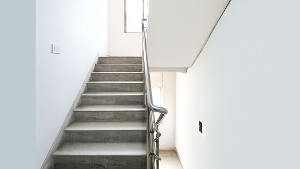 A staircase with a metal handrail leading to a landing. - Fabhotel Silverkey (Barasat)