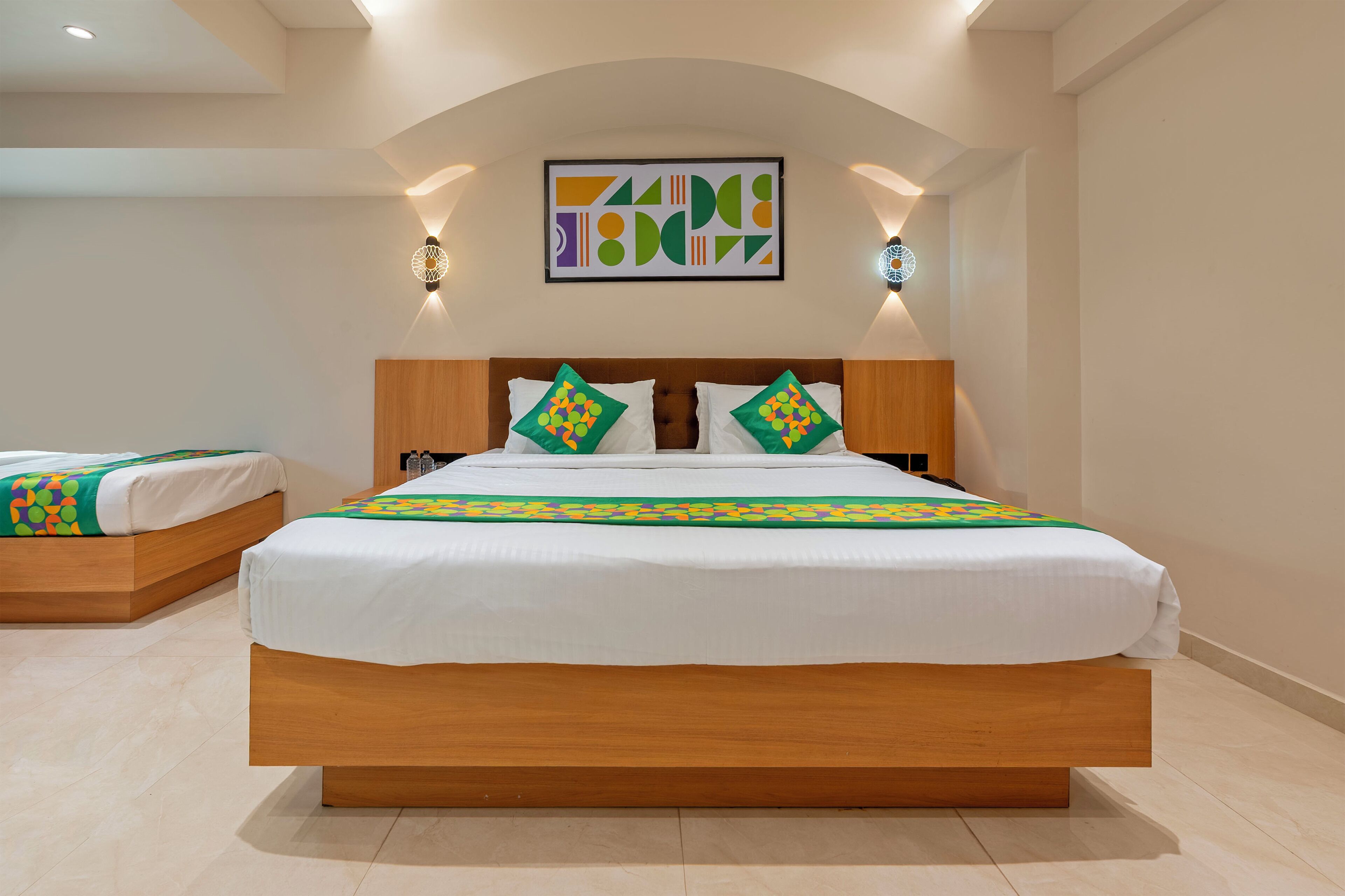 Ein Hotelzimmer mit einem großen Bett, zwei Nachttischen, einem Holzkopfteil und einem an der Wand befestigten Kunstwerk.