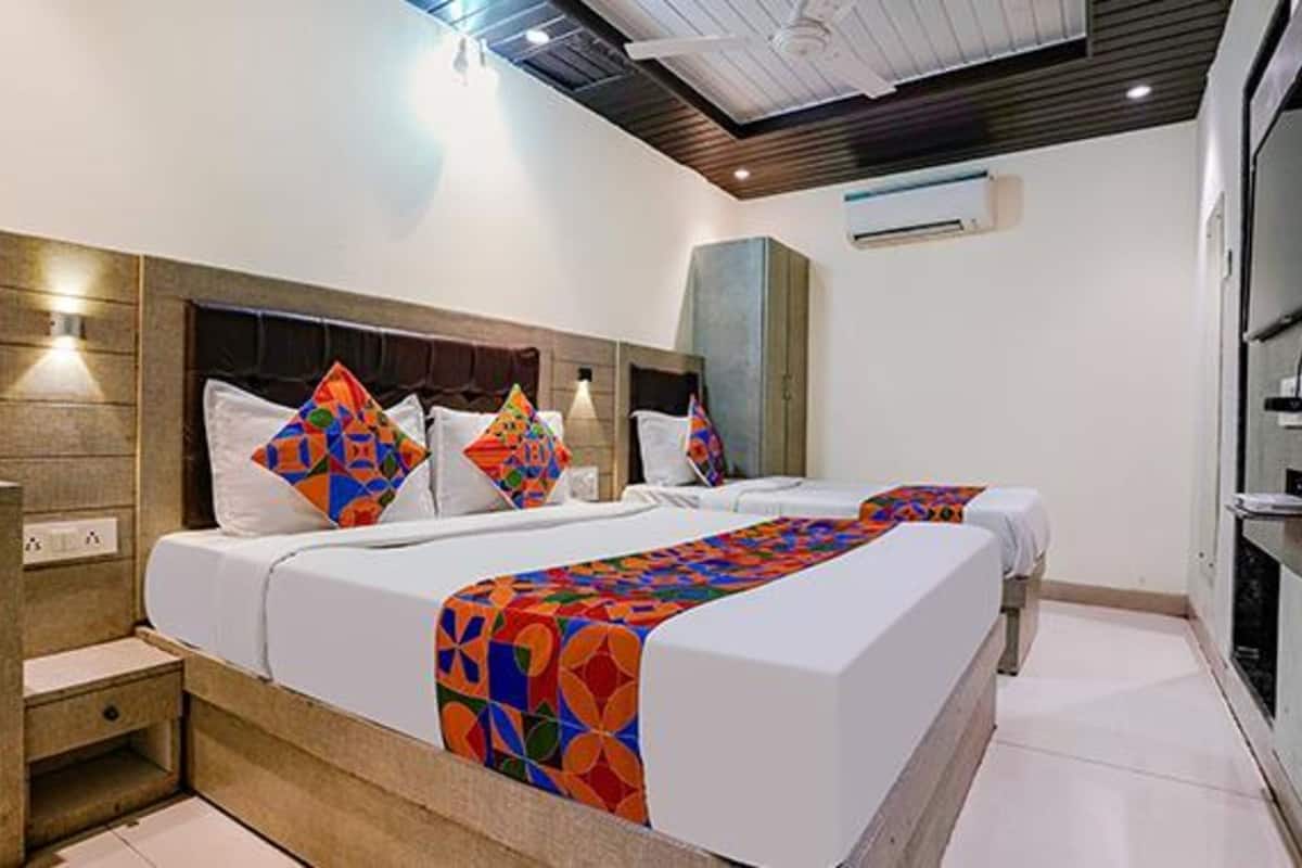 A hotel room with a modern design, featuring a large bed with colorful bedding, a wooden headboard, and a built-in wardrobe.