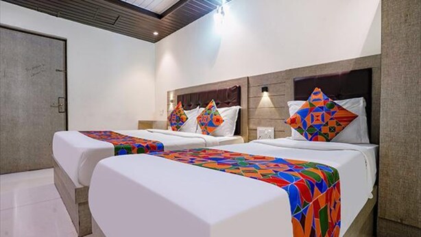 A hotel room with two beds, each with a colorful geometric-patterned bedspread and matching pillows. - Fabhotel New Prince Palace (Mumbai)