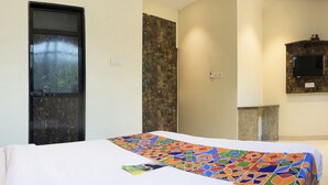 A hotel room with a bed, a door, a wall-mounted TV, and a window. - FabHotel Embassy Grand (Mumbai)