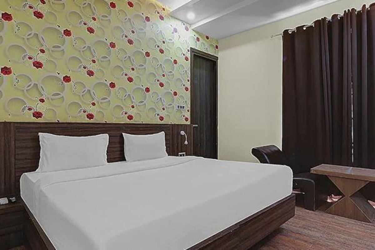 Habitación de hotel con una cama grande, un escritorio, una silla y una pared con estampado floral.