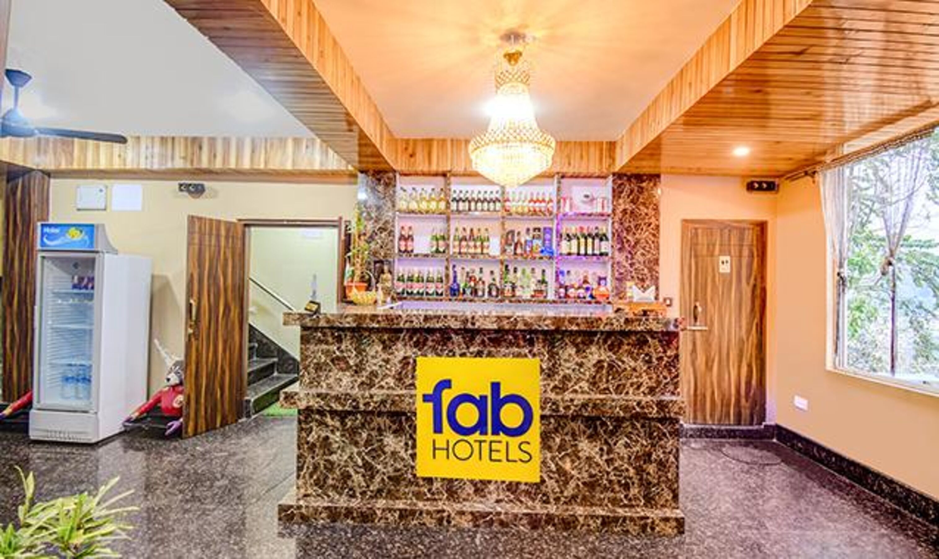 A hotel reception area with a marble counter, a chandelier, and a bar stocked with various bottles.