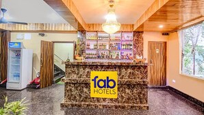Un hall d’accueil d’hôtel avec un comptoir en marbre, un lustre et un bar bien garni de différentes bouteilles.
