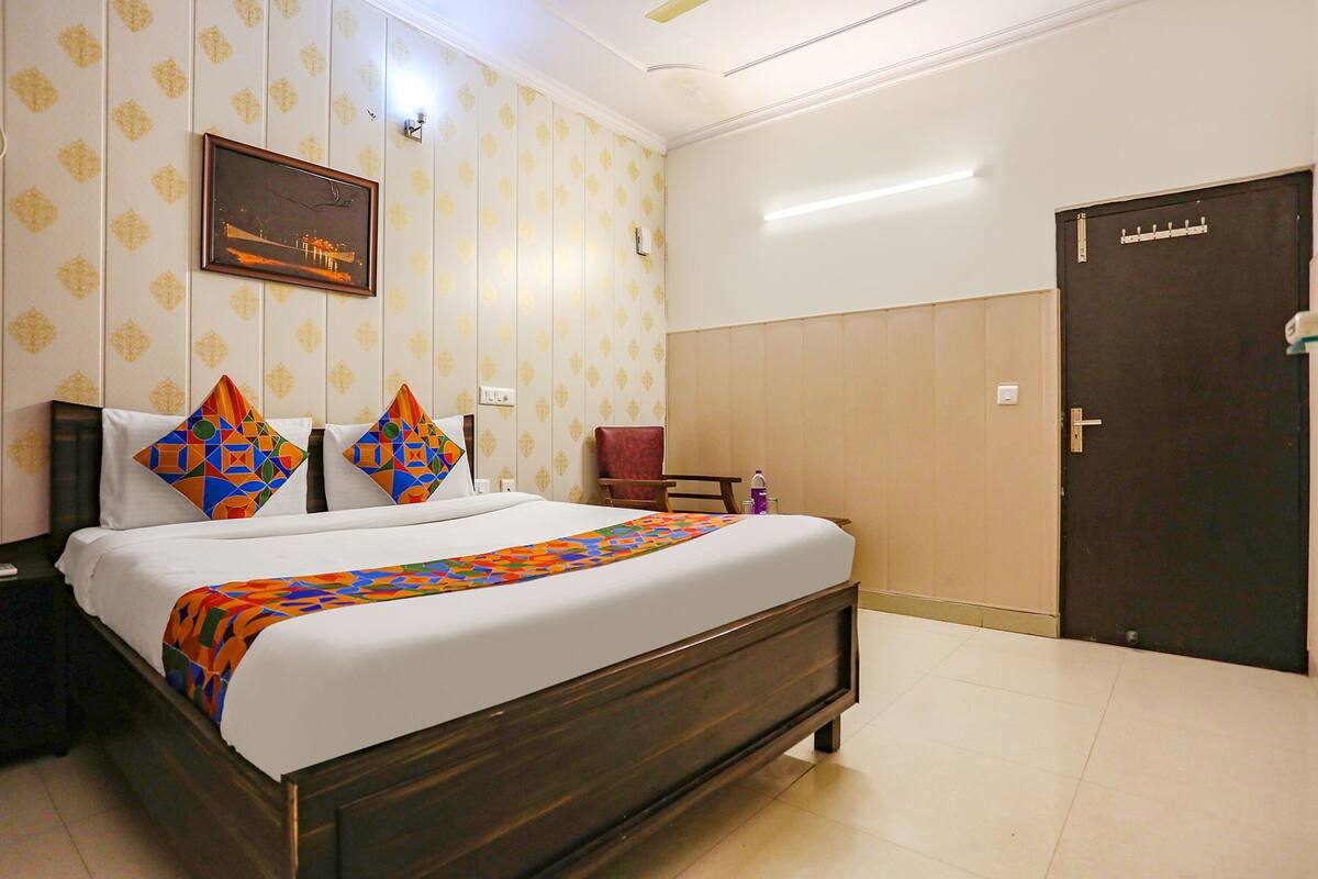 A hotel room with a large bed, a nightstand, a chair, a door, and a wall with patterned wallpaper.