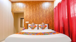 A neatly made bed with a colorful geometric-patterned bedspread and two decorative pillows. - FabHotel Limewood (Dehradun)