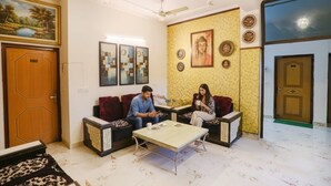A living room with a sofa set, a coffee table, and a painting on the wall. - FabHotel Limewood (Dehradun)
