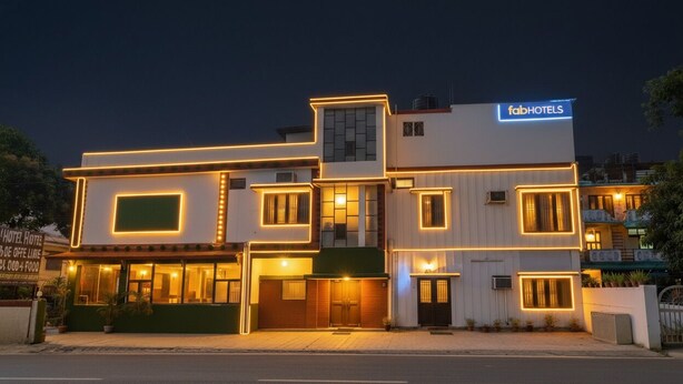 A modern multi-story building with a 'fabHOTELS' sign, featuring a prominent entrance with a glass facade and illuminated windows. - FabHotel Limewood (Dehradun)