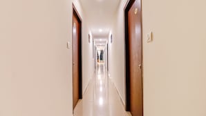 Un pasillo largo y estrecho con puertas de madera a ambos lados y un piso de baldosas brillantes.