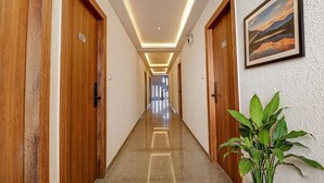 A hotel hallway with wooden doors, a plant, and a framed picture on the wall. - FabHotel Rotano Grand Marathahalli (Bengaluru)