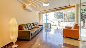 A modern interior with a leather sofa, a glass partition, and a view of the outside. - FabHotel Rotano Grand Marathahalli (Bengaluru)