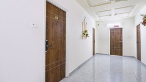 Ein Flur mit Holztüren, weißen Wänden und einem gefliesten Boden.