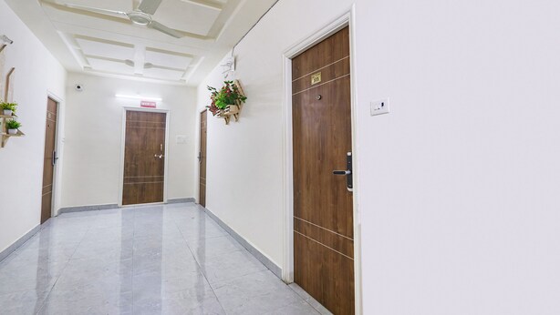 A hallway with a ceiling fan, wooden doors, and a sign indicating room number 105. - Fabhotel Golden Hitech (Hyderabad)