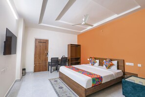 A bedroom with a bed, a desk, a chair, a wardrobe, and a ceiling fan. - Fabhotel Golden Hitech (Hyderabad)