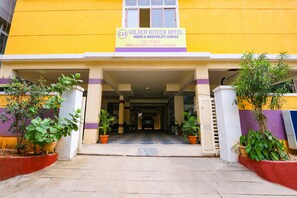 The entrance to Golden Hitech Hotel with a yellow facade, a signboard, and potted plants at the entrance. - Fabhotel Golden Hitech (Hyderabad)
