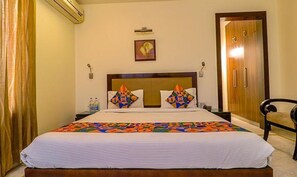 Una habitación de hotel con una cama, una silla, un armario y un cuadro en la pared.