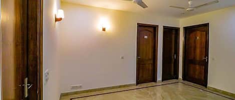 A spacious room with a marble floor, wooden doors, and ceiling fans.