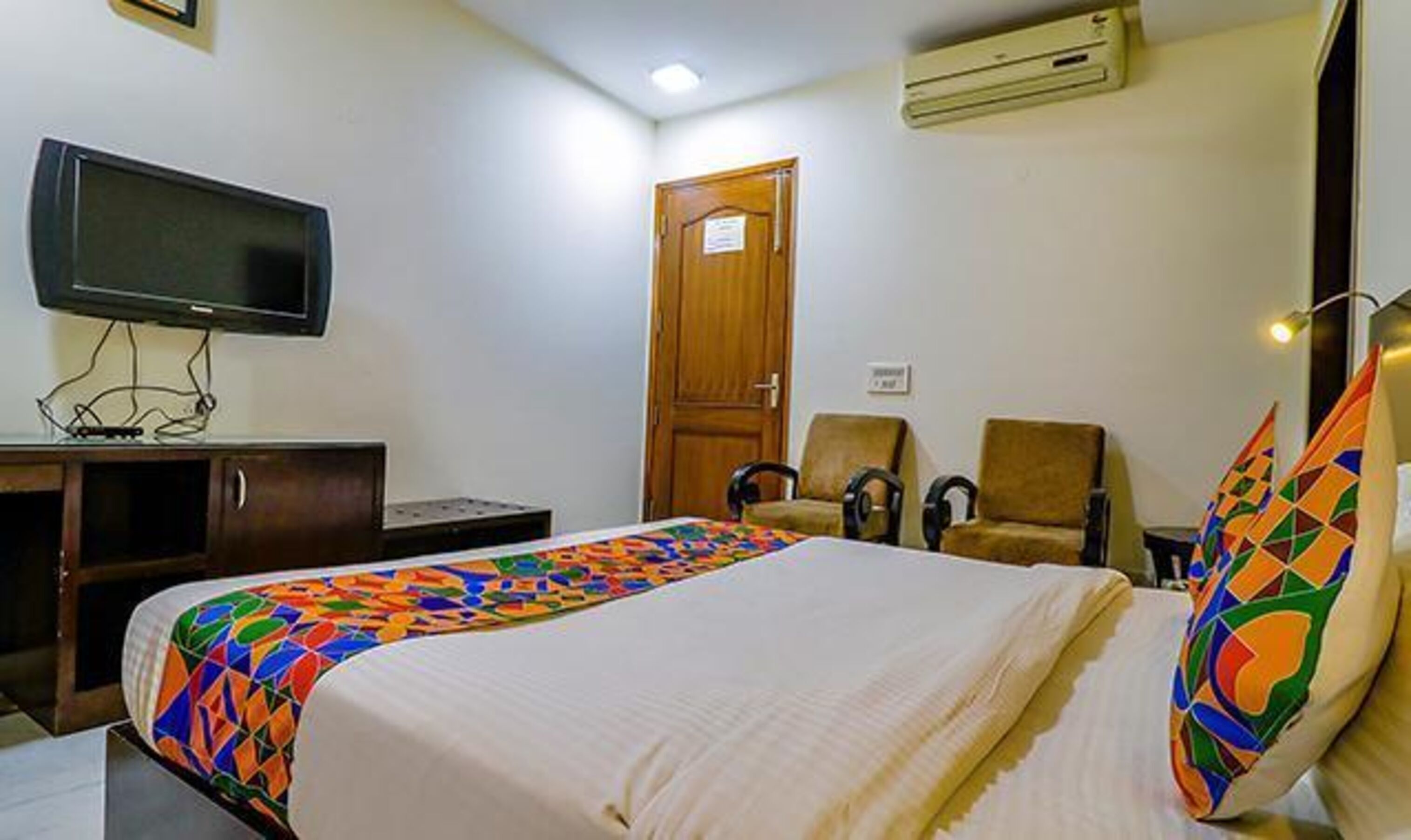 A hotel room with a bed, a television, a desk, and a chair.
