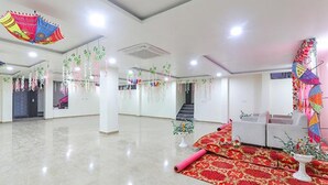A spacious hotel lobby with a red carpet, white sofas, and hanging decorations. - FabHotel The Gahmar Inn (Lucknow)