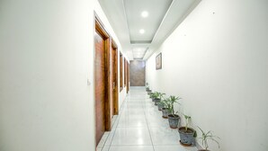 A hallway with wooden doors, potted plants, and a tiled floor. - Fabhotel Stevia (Dera Bassi)
