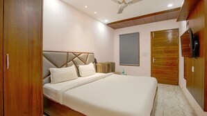 A bedroom with a large bed, wooden wardrobe, ceiling fan, and a small window. - Fabhotel Stevia (Dera Bassi)