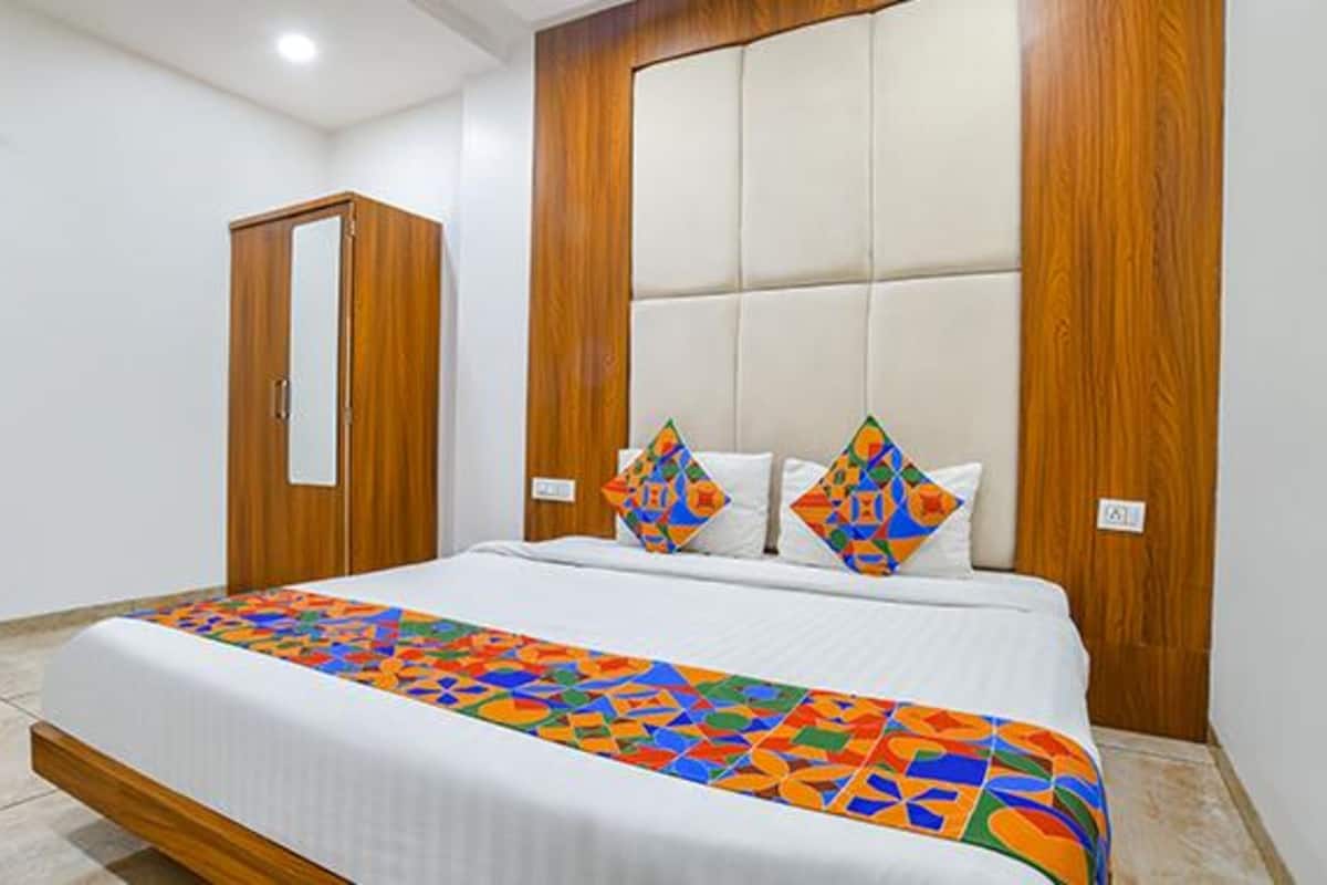 A hotel room with a large bed, a wooden wardrobe, and a grey armchair.
