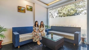 A modern lobby with a blue sofa, a glass coffee table, and two framed paintings on the wall. - Fabhotel Meera Palace (Indore)