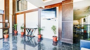 A lobby with a marble floor, potted plants, a wooden bench, and a large window. - Fabhotel Meera Palace (Indore)