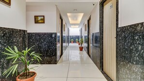 A hotel corridor with marble walls, potted plants, and a clean tiled floor. - Fabhotel Meera Palace (Indore)