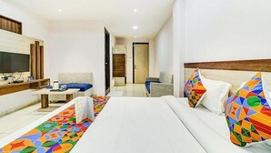 A hotel room with a bed, a desk, a TV, and a colorful rug. - Fabhotel Meera Palace (Indore)